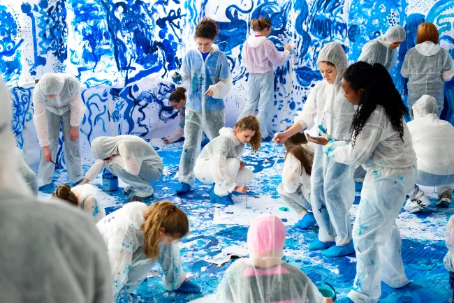 Children and adults creating blue patterns around a white room